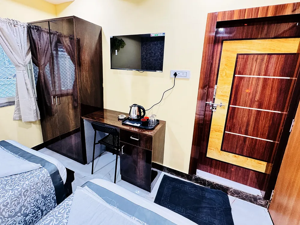 Guest room with a wall-mounted television, a desk with a kettle, and a wardrobe at Hotel Hyderabad Pulse